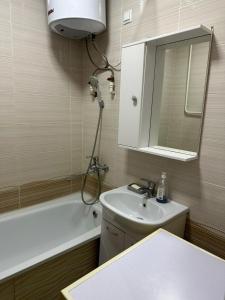 een badkamer met een wastafel en een spiegel en een douche bij Квартира люкс in Taraz