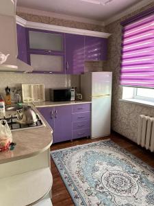 een keuken met paarse kasten en een witte koelkast bij Квартира люкс in Taraz