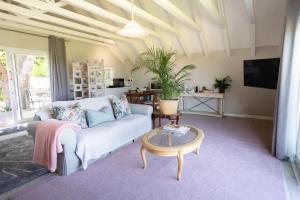 ein Wohnzimmer mit einem Sofa und einem Tisch in der Unterkunft Protea & Pincushion Cottages in Hermanus