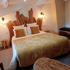 a bedroom with a large bed with a wooden headboard at LE GRAND LOGIS, chambre Santorin avec spa privatif 