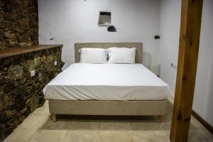 een slaapkamer met een bed met witte lakens en kussens bij Αρχοντικό Αλεξάνδρου in Kakopetria