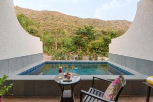 a patio with a table and a swimming pool at Anandam - Jacuzzi & Private Pool Villas in Udaipur in Udaipur