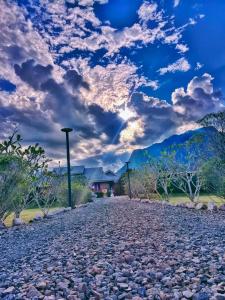 a gravel road leading to a house with a cloudy sky at The Wes Village, incl Breakfast and Dinner in Chiang Dao