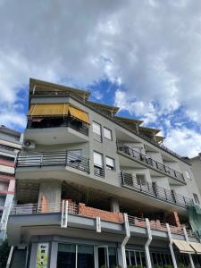 un edificio alto con balcones y un cielo azul en Stone City Apartament en Gjirokastër