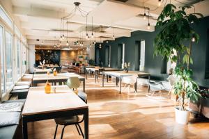 a dining room with tables and chairs and plants at Hostel by Hyve Basel in Basel