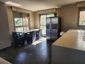 eine Küche mit einem Kühlschrank aus Edelstahl und einem Tisch in der Unterkunft YalaRent Haven villa with private pool and jacuzzi in Eilat
