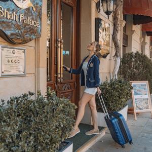 a woman walking out of a door with a suitcase at Shah Palace Luxury Museum Hotel in Baku