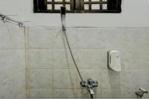 a water hose hooked up to a soap dispenser on a wall at Capital O 1362 Ciliwung Guest House Syariah in Malang