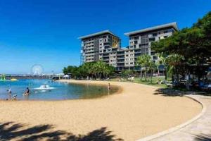 una playa con algunas personas en el agua y edificios en Luxury Waterfront Apartment (2 bedrooms) en Darwin