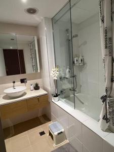 a white bathroom with a sink and a shower at Luxury Waterfront Apartment (2 bedrooms) in Darwin