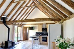 a kitchen with exposed beams and a table in a room at NEW Cosy cottage - Lake view & Log Burner - Dog proof garden in Rolvenden