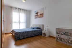 a white bedroom with a bed and a window at FiveStepsToSea - Beach Apartment Valencia in Valencia