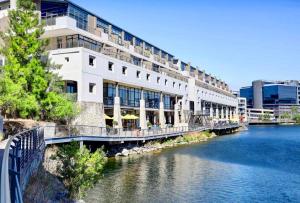a large white building with a bridge over a river at Meerendahl Luxury Apartments at Tyger Lake in Cape Town