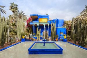 a blue building with a fountain in a yard with cactus at Riad HAFSSA & Spa in Marrakesh