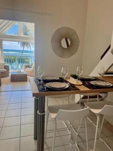 a dining room with a table and chairs with a view of the ocean at Ti MACLOA - Appartement les pieds dans l'eau in Sainte-Anne