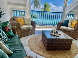 ein Wohnzimmer mit Korbstühlen und einem Tisch in der Unterkunft Ti MACLOA - Appartement les pieds dans l'eau in Sainte-Anne