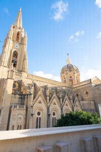 a large church with a clock tower on top of it at The White Knight Premium Boutique Hotel in Għajnsielem