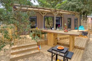 une terrasse dans le jardin avec une grande table en bois dans l'établissement Camping Signol, à Boyardville