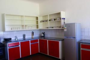 a kitchen with red cabinets and a refrigerator at Lovely 4 bed in Mutare - 2178 in Umtali