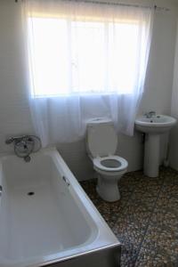 uma casa de banho com uma banheira, um WC e um lavatório. em Lovely 4 bed in Mutare - 2178 em Umtali