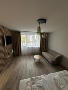 een woonkamer met een bed en een bank bij NERO apartamentai in Naujoji Akmenė