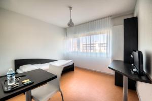 a hotel room with a bed and a desk with a television at Zenitude Hôtel-Résidences Les Hauts Du Chazal in Besançon