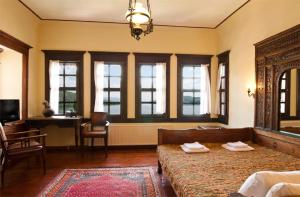 a bedroom with two beds and a desk and windows at Vergoula's Mansion in Kastoria