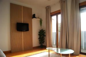 uma sala de estar com uma televisão e uma mesa de vidro em Studio no centro do Funchal no Funchal