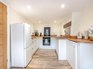 a kitchen with white cabinets and a white refrigerator at Ivy Cottage in Stanhope