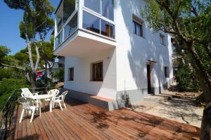 uma casa branca com um deque de madeira com uma mesa e cadeiras em Apartamento FRITZ em L'Estartit