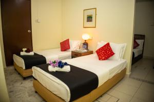 two beds in a hotel room with flowers on them at Sweet Inn Guest House in Kuantan