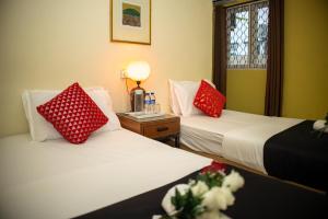 Sweet Inn Guest House في كُوانتان: سريرين في غرفة مع وسائد حمراء وبيضاء
