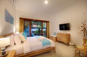 ein Schlafzimmer mit einem großen Bett und einem TV in der Unterkunft Villa Lotus Flower Sanur in Sanur