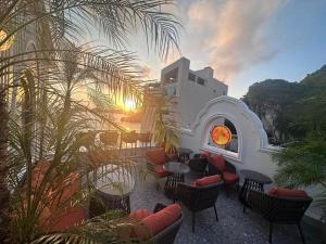 a patio with chairs and tables with the sunset in the background at The Moon Boutique Hotel Cat Ba in Cat Ba