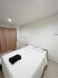 a white bed with a black bag on top of it at LILY HOMESTAY PUTATAN in Kota Kinabalu