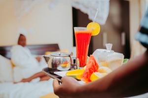 una persona sosteniendo una bandeja de comida con una bebida en City Hill Hotel en Buyumbura