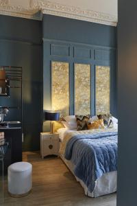 1 dormitorio con 1 cama con paredes y ventanas azules en 81 Promenade Studios, en Cheltenham