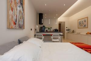 a bedroom with a white bed and a kitchen at Loft Marina in Fossano