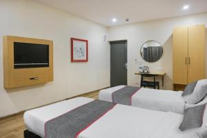 a hotel room with two beds and a flat screen tv at Townhouse 1118 The B&W Motel in Visakhapatnam