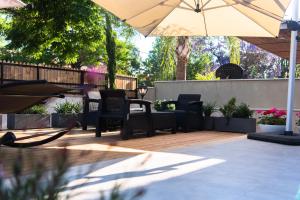 a patio with chairs and an umbrella at Ono Villa at Kiryat Ono in Qiryat Ono