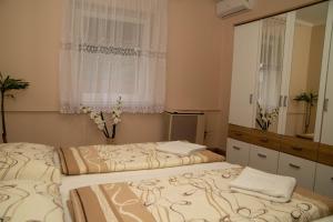 2 camas en un dormitorio con espejo y ventana en Boróka Vendégház Túrkeve en Túrkeve