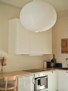 una cocina con armarios blancos y una gran lámpara. en Beautiful design studio in the heart of Kallio en Helsinki