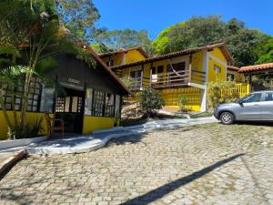 a car parked in front of a yellow house at Hotel Pousada Recanto das Árvores in Búzios