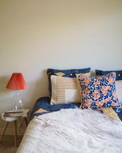 cama con almohadas y mesa con lámpara en Beautiful design studio in the heart of Kallio, en Helsinki