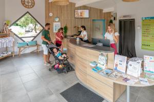 a group of people standing around a store with a baby in a stroller at Camping Signol in Boyard-Ville