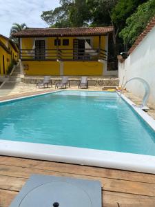 a swimming pool in front of a yellow house at Hotel Pousada Recanto das Árvores in Búzios