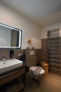 ein Badezimmer mit einem Waschbecken, einem WC und einem Spiegel in der Unterkunft Hofer Stubn in Kolsassberg