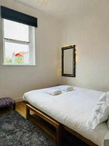 a bedroom with a bed with a mirror and a window at Stylish city flat with private parking in Bristol