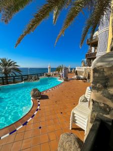 einen Pool mit zwei Stühlen und das Meer in der Unterkunft Amazing Apartment Altamar 2 in Playa del Aguila