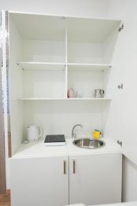 a small white kitchen with a sink and shelves at Neapolitan Soul By Dimorra in Naples +63 photos